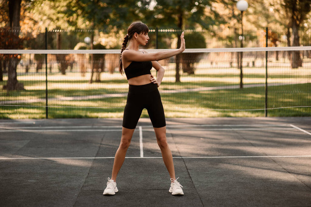 A young female trainer performs a fitness compression exercise. The girl is working out outdoors. Healthy lifestyle. High quality photo - Photo, Image