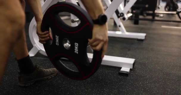 Чоловік розміщує важкі 20 кг залізної ваги на штанзі для хардкорної важкої атлетики в тренажерному залі або підйомі. Крос-тренінги та спорт - Кадри, відео