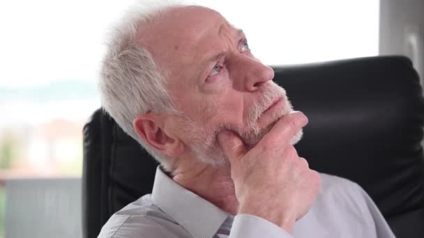 Portret troskliwego starszego biznesmena siedzącego w biurze - Materiał filmowy, wideo