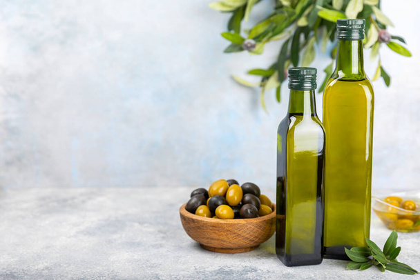 Huile d'olive dans une bouteille sur fond de texture. Bouteille d'huile avec branches et fruits d'olives. Endroit pour le texte. espace de copie. huile de cuisson et vinaigrette. - Photo, image