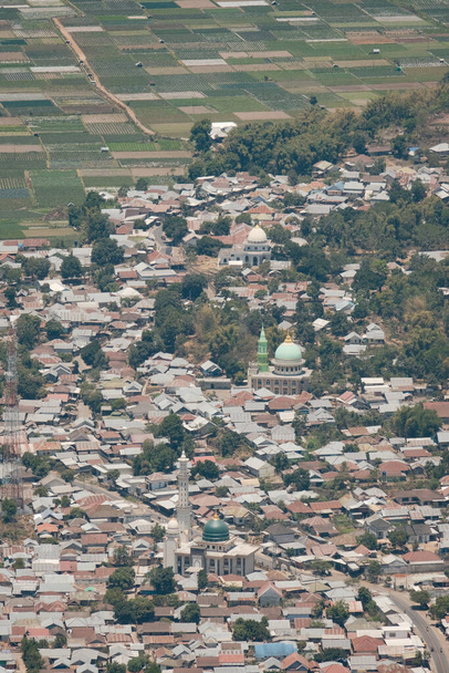 Diese Luftaufnahme fängt den komplexen Wandteppich von Sembalun ein und zeigt seine charmanten Häuser und Moscheen inmitten der Umarmung der Natur. - Foto, Bild