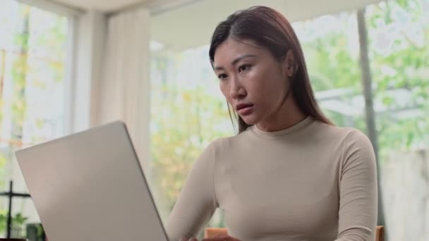 Mediana toma de solopreneur joven mujer analizando los datos en el ordenador portátil mientras trabaja desde casa - Metraje, vídeo