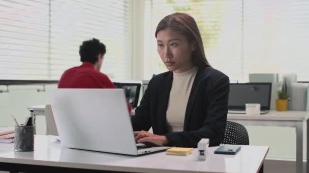 Μεσαία φωτογραφία πορτραίτου γυναικών υπαλλήλων γραφείου που στέλνουν μηνύματα σε πελάτες στο laptop και κοιτάζουν την κάμερα - Πλάνα, βίντεο