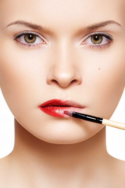 Close-up frontal portrait of beautiful woman model applying lipstick - Fotoğraf, Görsel