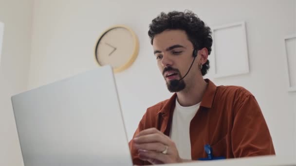 Média foto de empresário em fone de ouvido compartilhando suas ideias com colegas de trabalho durante videochamada no laptop - Filmagem, Vídeo