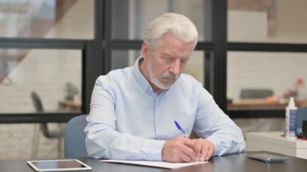 Oude zakenman die een brief in kantoor schrijft - Video