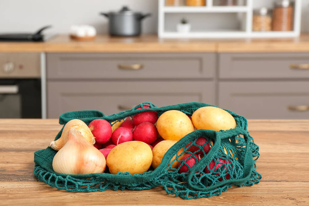Mutfaktaki tezgahta farklı taze sebzelerin olduğu ağ torbası, yakın plan. - Fotoğraf, Görsel