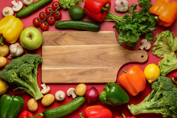 Wooden board with fresh vegetables, fruits and mushrooms on red background - Photo, Image