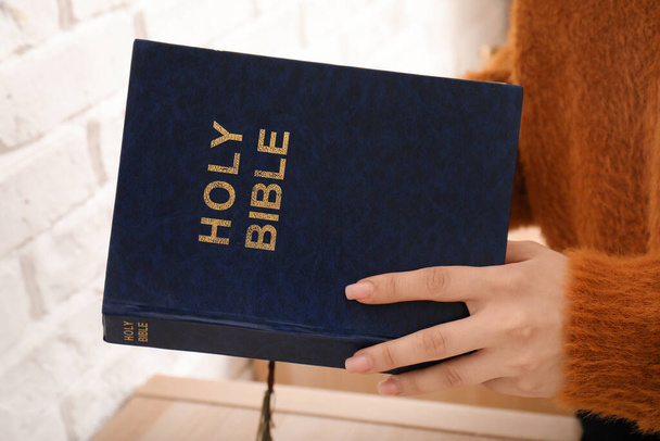 Young woman with Bible in living room, closeup - Photo, Image