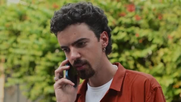close-up van de man bellen zijn vriend op smartphone terwijl het hebben van wandeling in het park in de zomer dag - Video