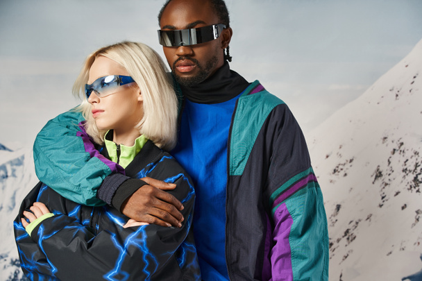 山の背景,冬のコンセプトと活気に満ちたメガネで暖かい服でポーズするスタイリッシュなカップル - 写真・画像