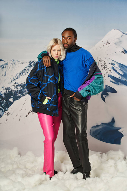 modish multiracial couple in stylish warm attire hugging and looking at camera, winter concept - Фото, зображення