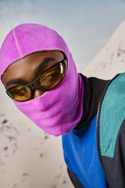 portrait of young stylish man in pink warm balaclava mask with snowy background, winter concept - Photo, Image