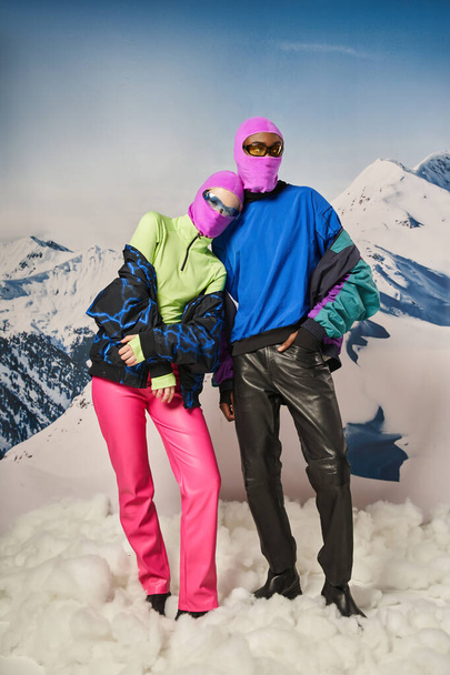 beautiful couple posing together wearing pink balaclavas and stylish sunglasses, winter concept - Photo, Image