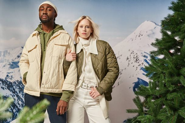 stylový multikulturní pár v teple modish oblečení pózování a pohled na kameru, zimní koncept - Fotografie, Obrázek