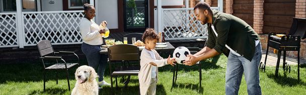 családi hétvégi banner, boldog afro-amerikai apa ad focilabdát a fiának a ház hátsó udvarán - Fotó, kép