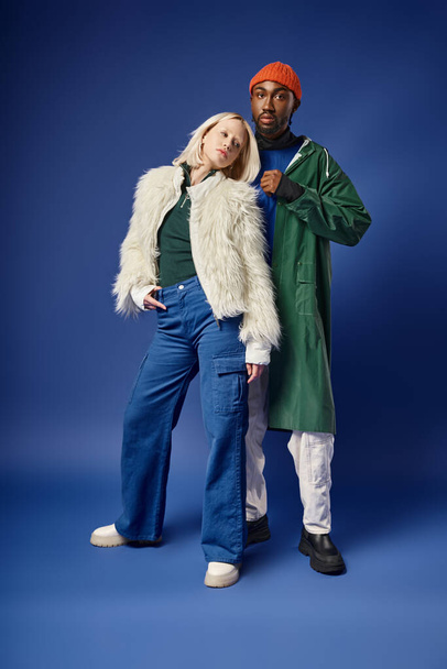 multiethnic couple posing in winter attire with mountain on backdrop, african american man and woman - Fotó, kép