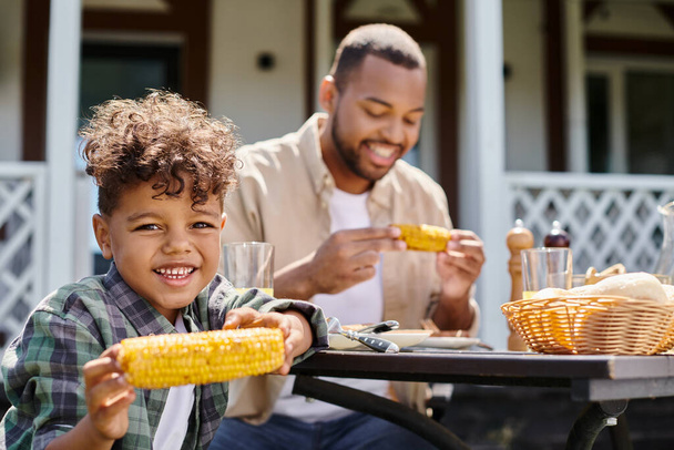 весела афроамериканська дитина має сімейний барбекю з батьком на задньому дворі будинку, апельсиновий сік - Фото, зображення