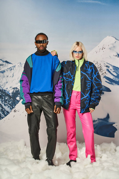 pareja multiétnica posando en traje de invierno con la montaña en el telón de fondo, hombre y mujer afroamericanos - Foto, imagen