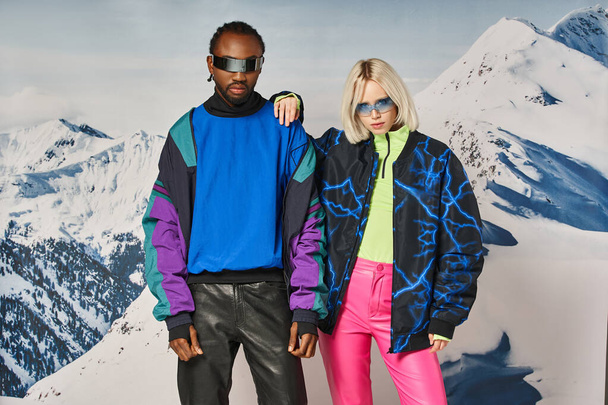 pareja multiétnica posando en traje de invierno con la montaña en el telón de fondo, hombre y mujer afroamericanos - Foto, Imagen