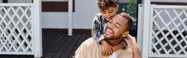 positivo afro-americano miúdo abraçando pai enquanto tendo bbq no quintal da casa, banner - Foto, Imagem