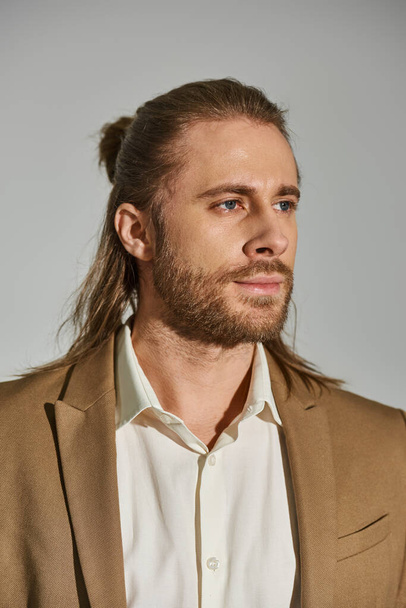 Porträt eines gut aussehenden Geschäftsmannes in weißem Hemd mit beigem Blazer auf grauem Hintergrund - Foto, Bild