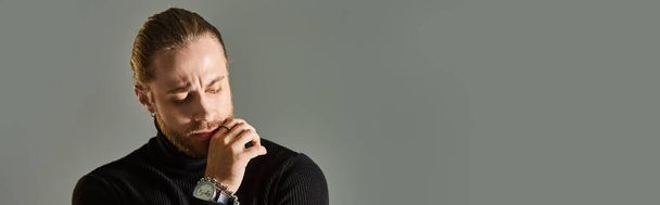 zamyšlený muž v roláku svetr drží ruku u brady a odvrací pohled na šedé pozadí, prapor - Fotografie, Obrázek