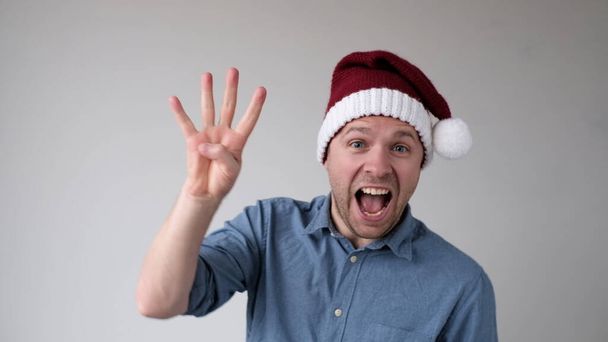 Hombre divertido en un año nuevo Sombrero cuenta los dedos, como muestra números. Captura de estudio - Foto, imagen
