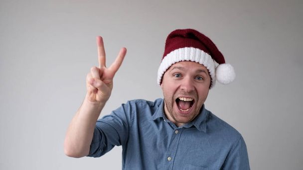 Zabawny człowiek w noworocznym kapeluszu liczy palce, jak numery pokazów. Zdjęcia studyjne - Zdjęcie, obraz