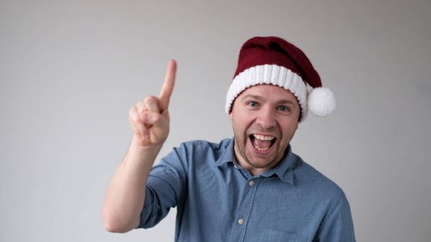Zabawny człowiek w noworocznym kapeluszu liczy palce, jak numery pokazów. Zdjęcia studyjne - Zdjęcie, obraz