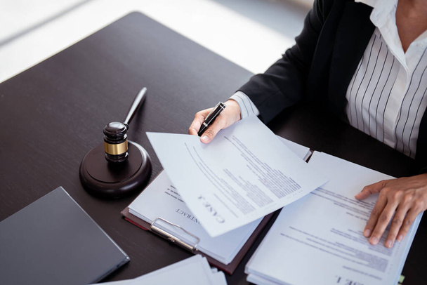 Lawyer businesswoman holding document to reading lawsuit and checking about financial business data while analysis about legislation agreement and terms data of business contract in law firm. - Photo, Image