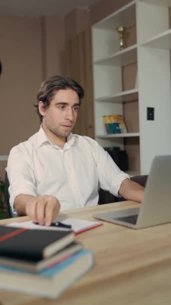 Фрілансер Чоловік працює або вивчає дистанційно, використовуючи ноутбук сидячи на робочому столі в домашньому офісі - Кадри, відео