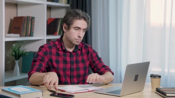  Homem Freelancer trabalhando ou estudando remotamente, usando laptop sentado no desktop no escritório em casa - Filmagem, Vídeo