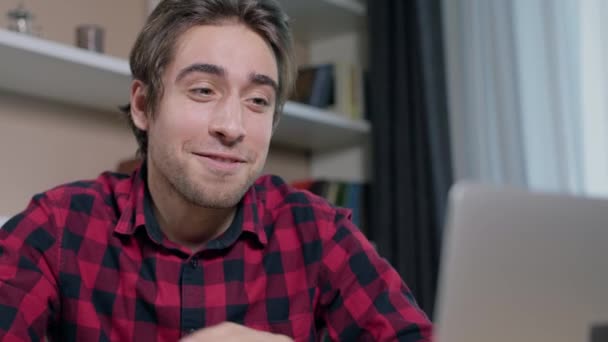 Nuori mies, jolla on hauskaa videopuhelu jonkun kanssa käyttäen hänen kannettavaa tietokonettaan - Materiaali, video