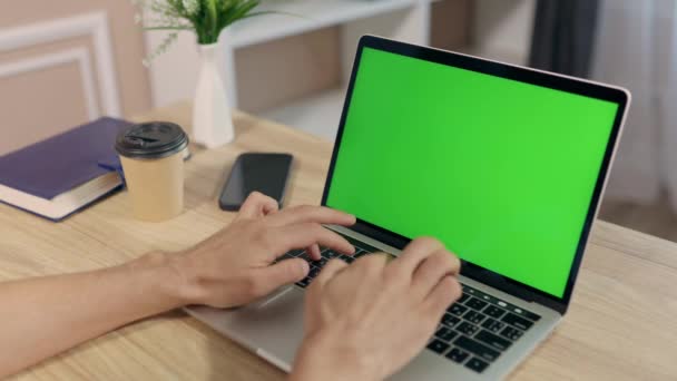 Jeune homme utilise un ordinateur portable avec écran vert maquillé pour le travail ou l'étude dans le bureau à domicile confortable. Gros plan de l'affichage de la clé Chroma - Séquence, vidéo