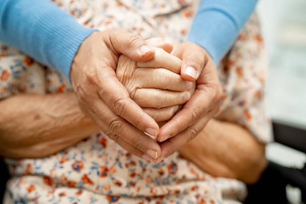 Caregiver holding hands Asian elderly woman patient with love, care, encourage and empathy at nursing hospital, healthy strong medical concept. - Fotó, kép