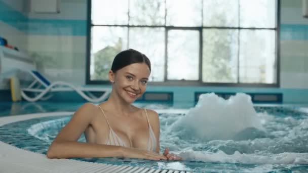 Pretty young woman relaxing in hydro massage pool. Spa center leisure routine. Female sportswoman enjoying bubble bath to relax after training class - Footage, Video