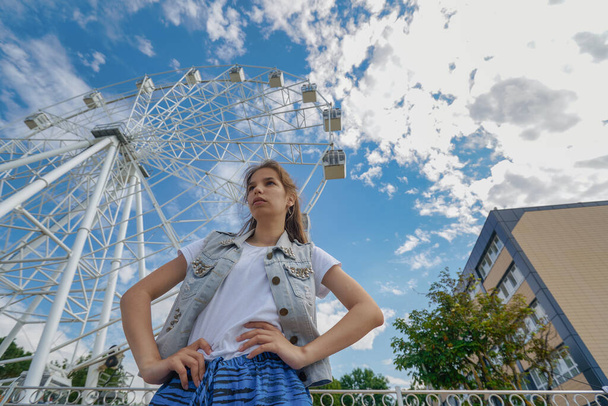 Outdoor portrait of young caucasian teenager with Ferris wheel in the background in Zelenogradsk. - Foto, Imagen