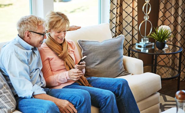 Τηλέφωνο, ώριμο ή ευτυχισμένο ζευγάρι στα μέσα κοινωνικής δικτύωσης στον καναπέ για επικοινωνία, meme ή σύνδεση στο διαδίκτυο. Αρχική σελίδα, ηλικιωμένος άνδρας ή γυναίκα στο κινητό app για να αναζητήσετε, να χαλαρώσετε ή να μετακινηθείτε online στον καναπέ στο σαλόνι. - Φωτογραφία, εικόνα