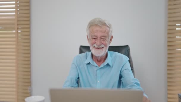幸せな古い引退した白人ビジネスマンは、自宅でラップトップでオンラインで作業しながら笑顔. - 映像、動画