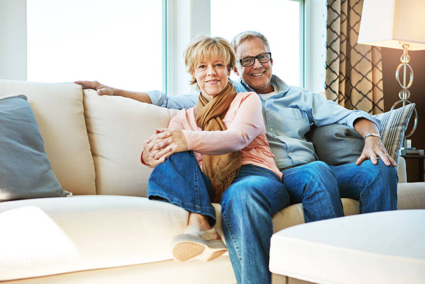 Relax, retirement and portrait of couple on sofa for bonding, healthy relationship and marriage. Happy, home and senior man and woman hug on couch for love, commitment and embrace in living room. - Photo, Image