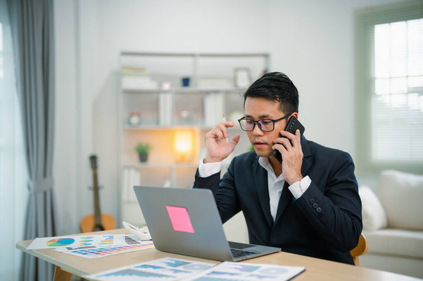 Freelance business man calling on mobile smartphone while working with laptop on table, businessman mobile phone to calling with customers or shopping online. Smart phone conversation conferrence. - Photo, Image