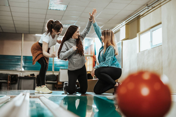 Tre allegre giovani donne si divertono e celebrano il loro punteggio nel bowling club. - Foto, immagini