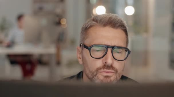 Focus, mature and businessman working in the office late with computer for web design project. Technology, deadline and male designer with overtime doing research on a desktop in workplace at night - Footage, Video