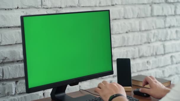 Barbudo hombre de mediana edad que trabaja en la computadora de escritorio con Green Mock Up Screen. Interior- Oficina moderna con pared de ladrillo blanco - Imágenes, Vídeo