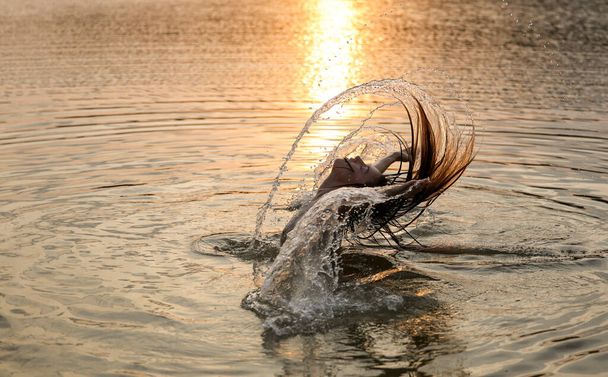 Nuori kaunis tyttö rentouttava kylpy järvessä ennen kultaista auringonlaskua - Valokuva, kuva