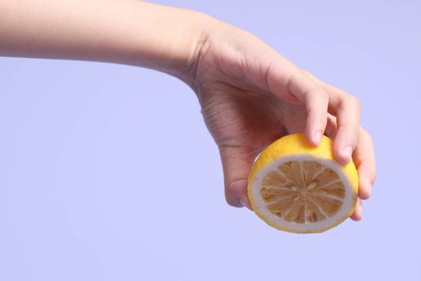 A mão mulher asiática segurando limão no fundo roxo. - Foto, Imagem