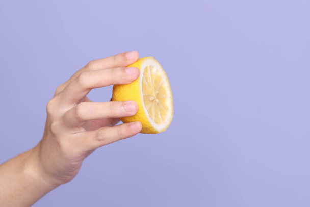 The Asian woman hand holding lemon in the purple background. - Photo, Image