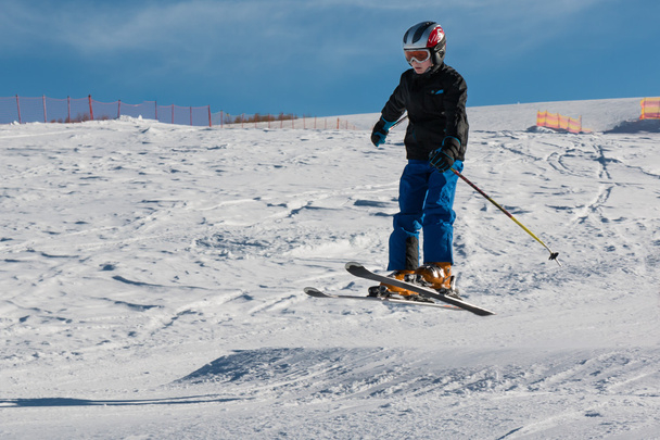 Kleine skiër voert sprong in de sneeuw - Foto, afbeelding