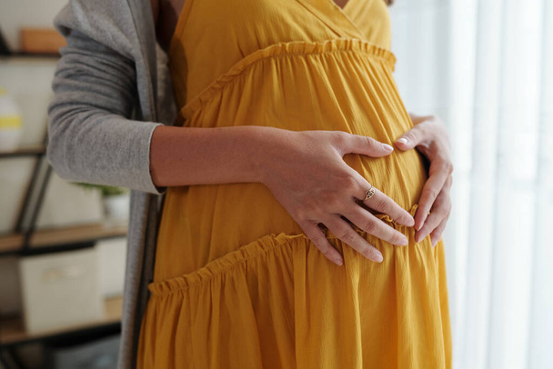 妊娠中の女性は腹に手を置くときに心のジェスチャーを作ります - 写真・画像